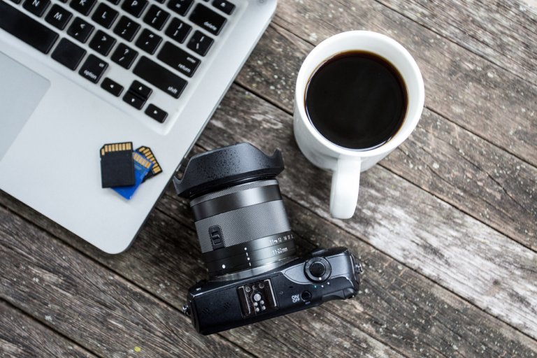 Laptop with digital camera and a coffee cup.